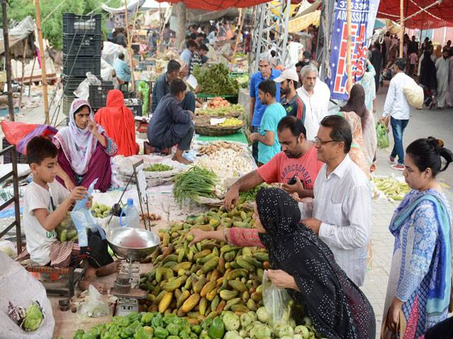 Pakistani shoppers purchase vegetables from a stall inside a